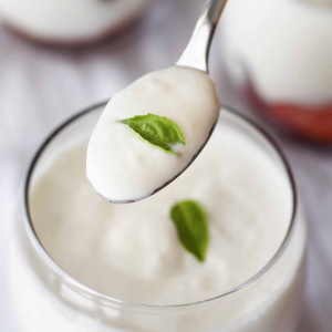 close-up-hand-holding-spoon-with-yogurt+